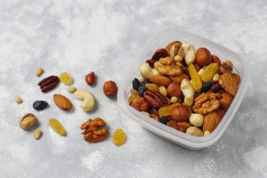 Assortment of nuts in plastic container. Cashew, hazelnuts, waln